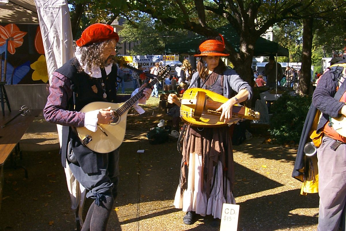 A man and a woman who are playing musical instruments at Arts Alive.