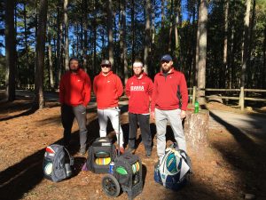 Four men standing beside their disc golf gear before they play a game of disc golf at the newest course at McFarland Park in Florence, Alabama.